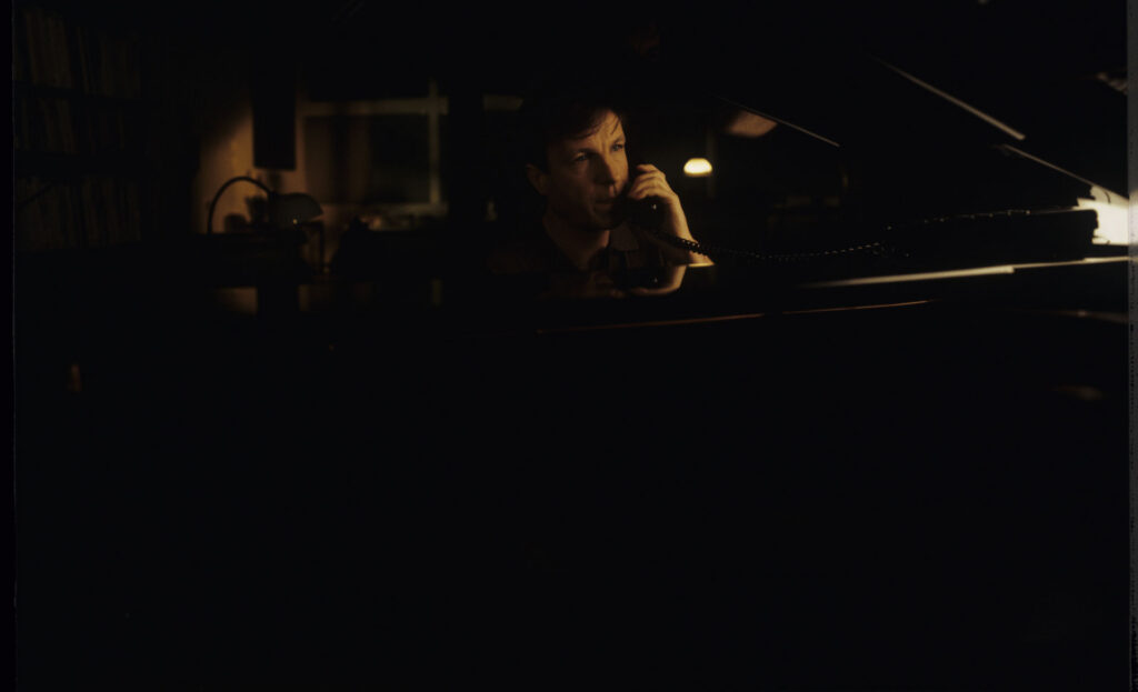 Olivier (Benoit Regent) at the piano in his apartment while talking to Julie on the phone.