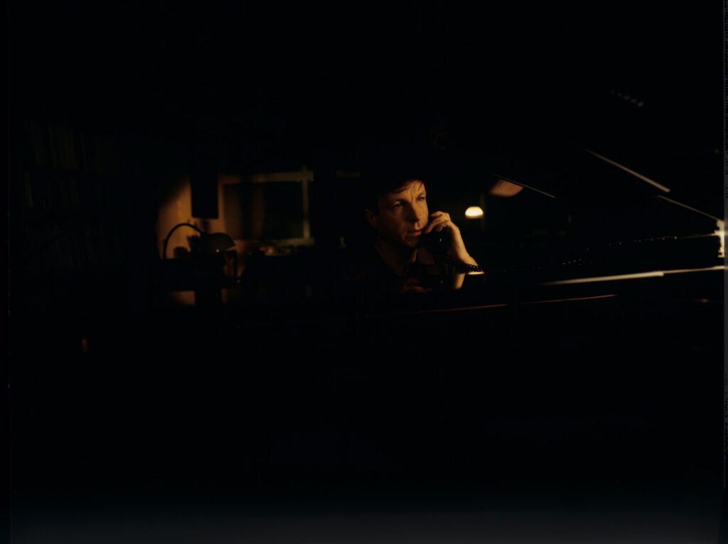 Olivier (Benoit Regent) at the piano in his apartment while talking to Julie on the phone.
