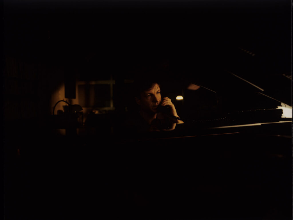 Olivier (Benoit Regent) at the piano in his apartment while talking to Julie on the phone.