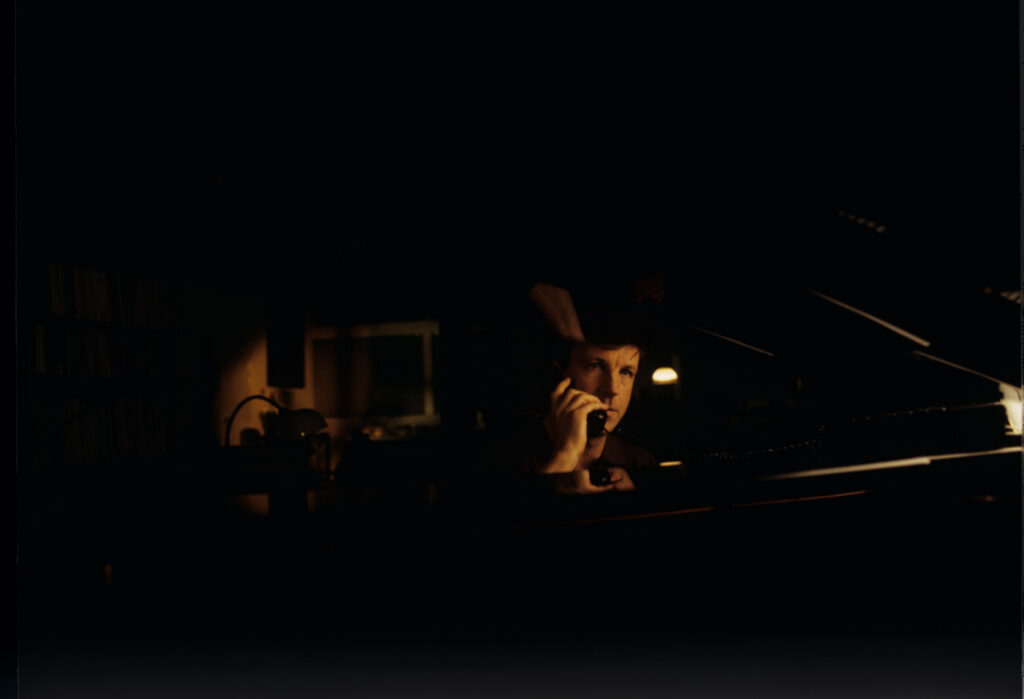 Olivier (Benoit Regent) at the piano in his apartment while talking to Julie on the phone.