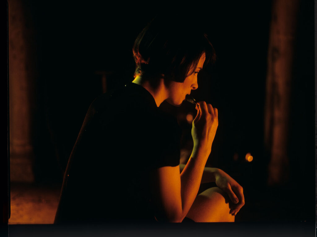 Julie (Juliette Binoche) takes a blue lollipop from her purse in front of the fireplace in an emptied room.