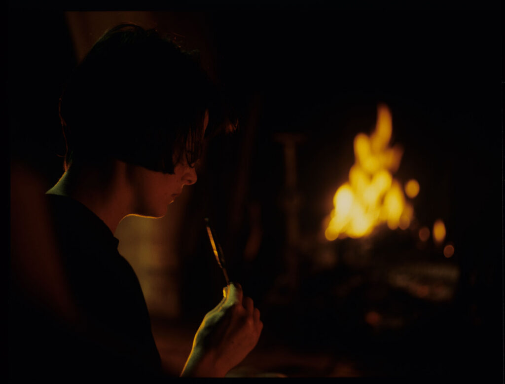 Julie (Juliette Binoche) takes a blue lollipop from her purse in front of the fireplace in an emptied room.