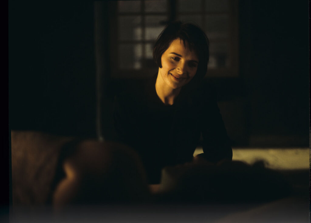Julie (Juliette Binoche) watches Olivier (Benoit Regent) sleep after spending the night with him.