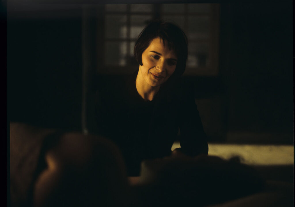 Julie (Juliette Binoche) watches Olivier (Benoit Regent) sleep after spending the night with him.