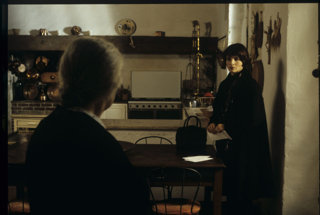 Julie (Juliette Binoche), after leaving the hospital, talks to a maid (Isabelle Sadoyan) in the kitchen of her mansion.
