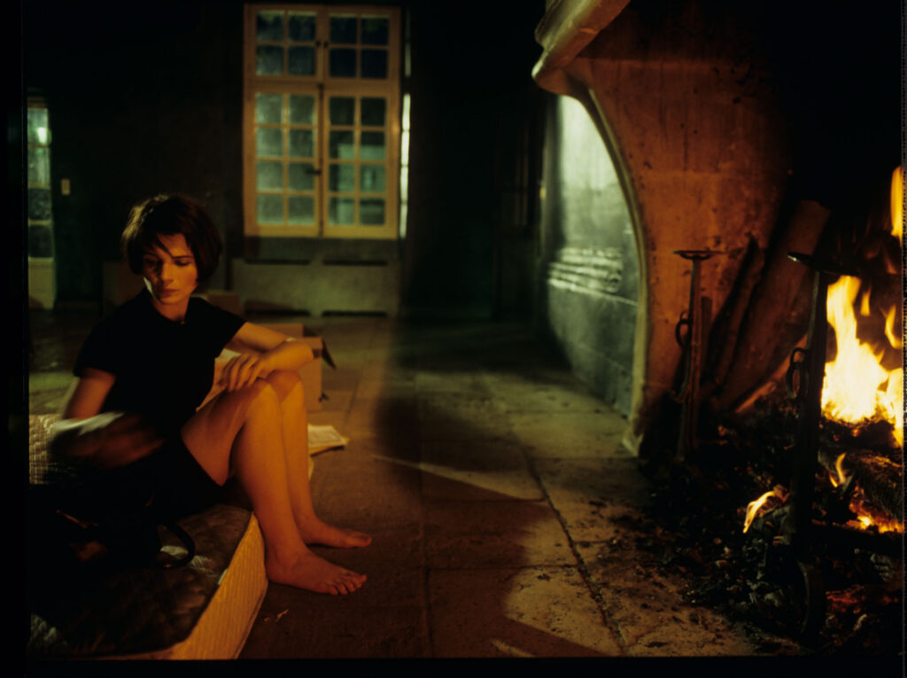 Julie (Juliette Binoche) in front of the fireplace in her big house, which was emptied and only the mattress remained.