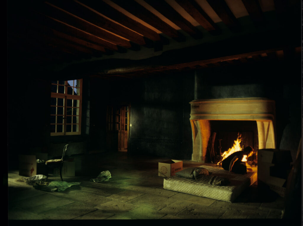 Julie (Juliette Binoche) in front of the fireplace in her big house, which was emptied and only the mattress remained.