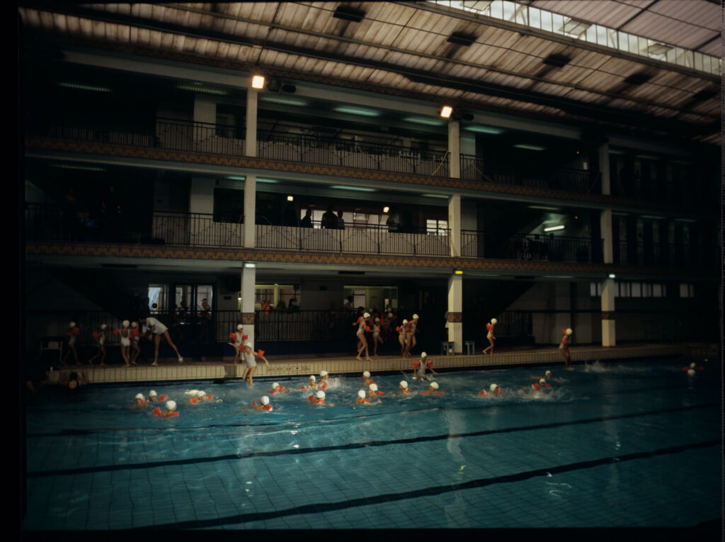 Grupa dzieci na basenie Piscine Pontoise w Paryżu, gdzie Julie, główna bohaterka filmu, systematycznie pływa.