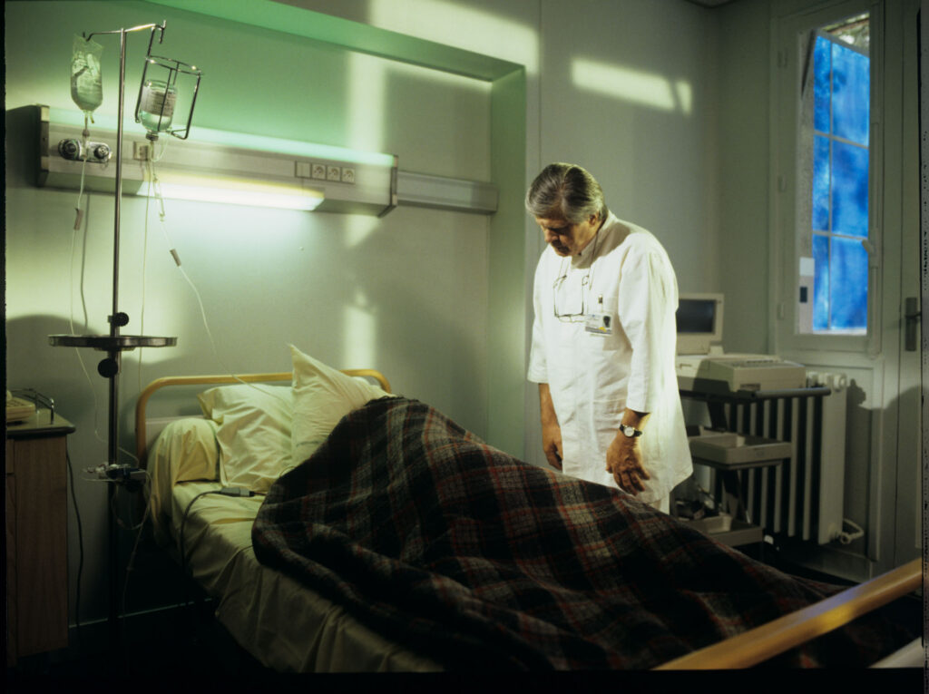 Doctor (Claude Duneton) informs Julie (Juliette Binoche) about the death of her husband and daughter.