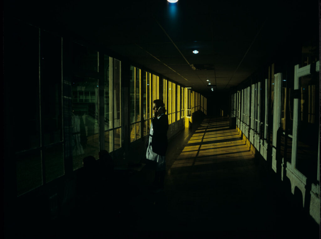 The nurse (Idit Cebula), alarmed by the noise in the hallway, notices a broken window and calls security.