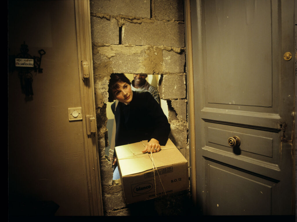 Julie (Juliette Binoche) enters her new apartment with a package with a blue chandelier.