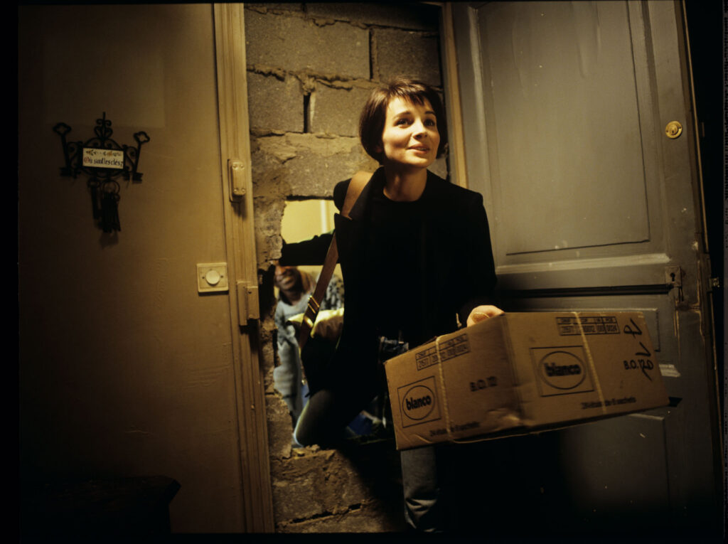 Julie (Juliette Binoche) enters her new apartment with a package with a blue chandelier.