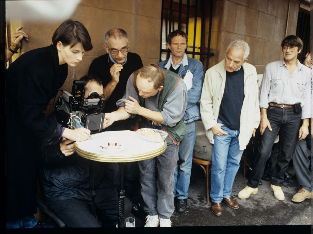 Ekipa na planie zdjęciowym na paryskiej ulicy podczas kręcenia sceny zapisywania przez Julie nut na stoliku kawiarnianym.
