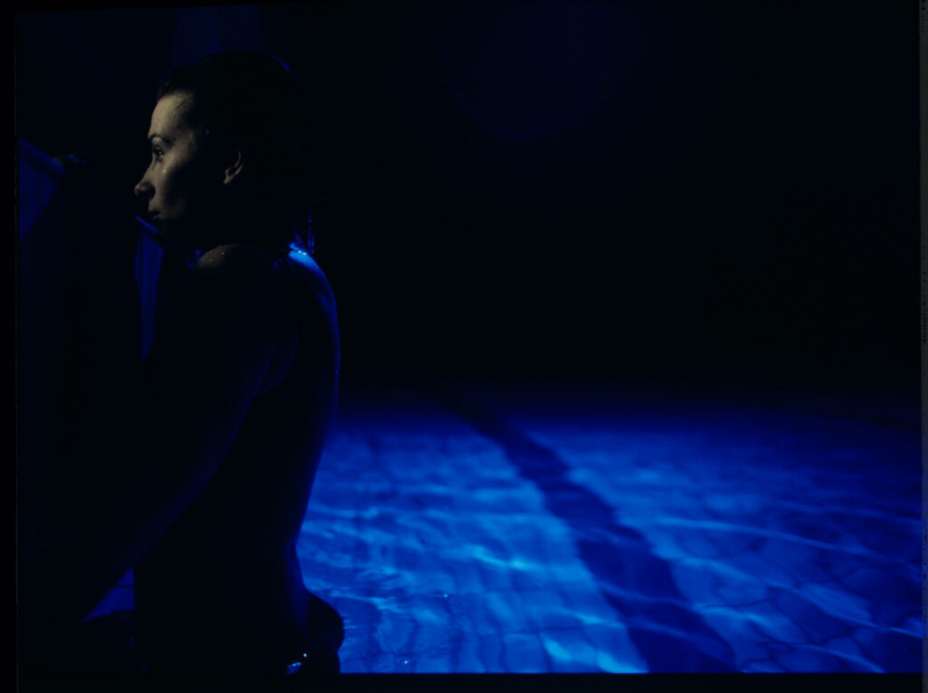 Julie (Juliette Binoche) in a blue glow, where she releases accumulated emotions while swimming.