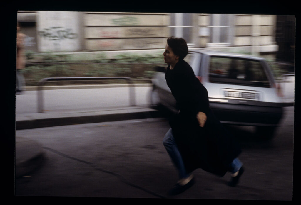 Julie (Juliette Binoche) is running on the street to catch Olivier's departing car.