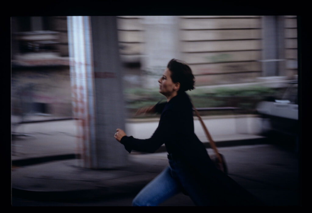 Julie (Juliette Binoche) is running on the street to catch Olivier's departing car.