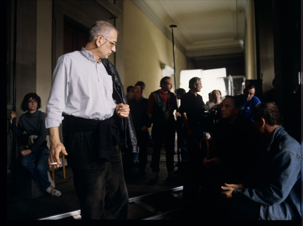 Krzysztof Kieślowski (reżyser) w otoczeniu ekipy na planie zdjęciowym na korytarzu sądu.