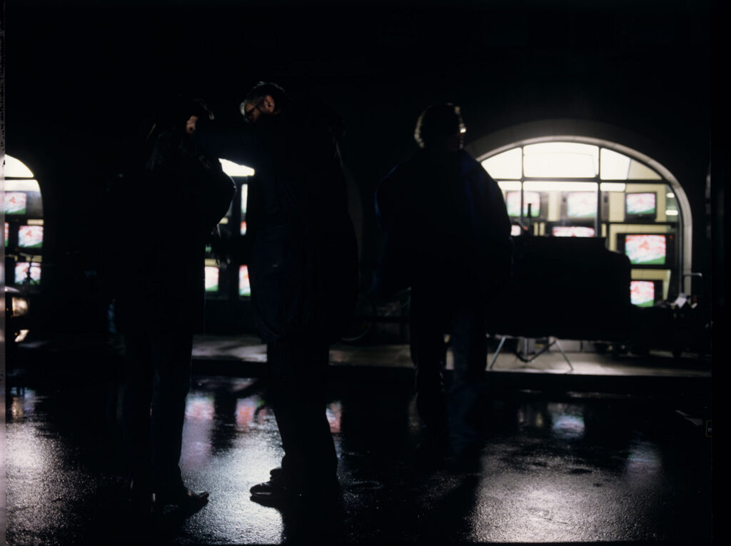The crew on set on a rain-drenched street. The film crew prepares to shoot a scene.