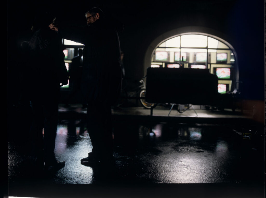 The crew on set on a rain-drenched street. The film crew prepares to shoot a scene.