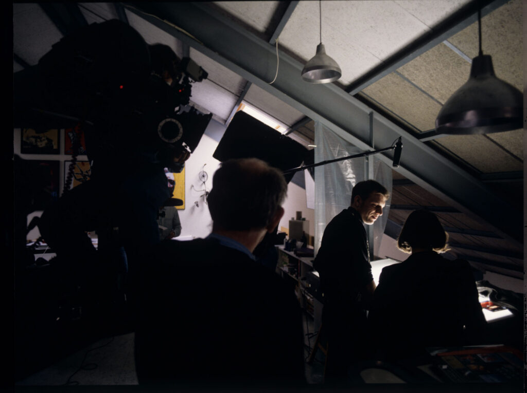 Shooting a scene in a photography studio where photographer Samuel Le Bihan asks Valentine to select photos for an billboard.