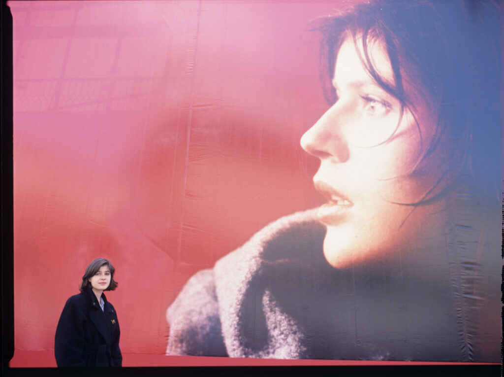 Irène Jacob in front of an advertising billboard with the likeness of her film heroine.