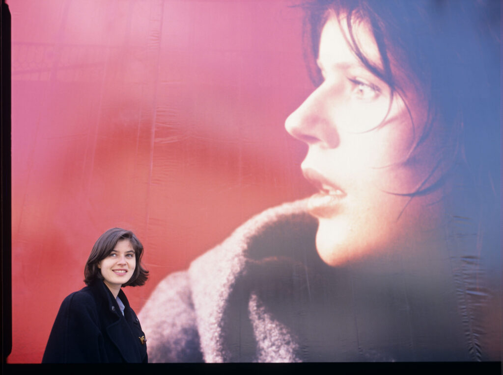 Irène Jacob in front of an advertising billboard with the likeness of her film heroine.