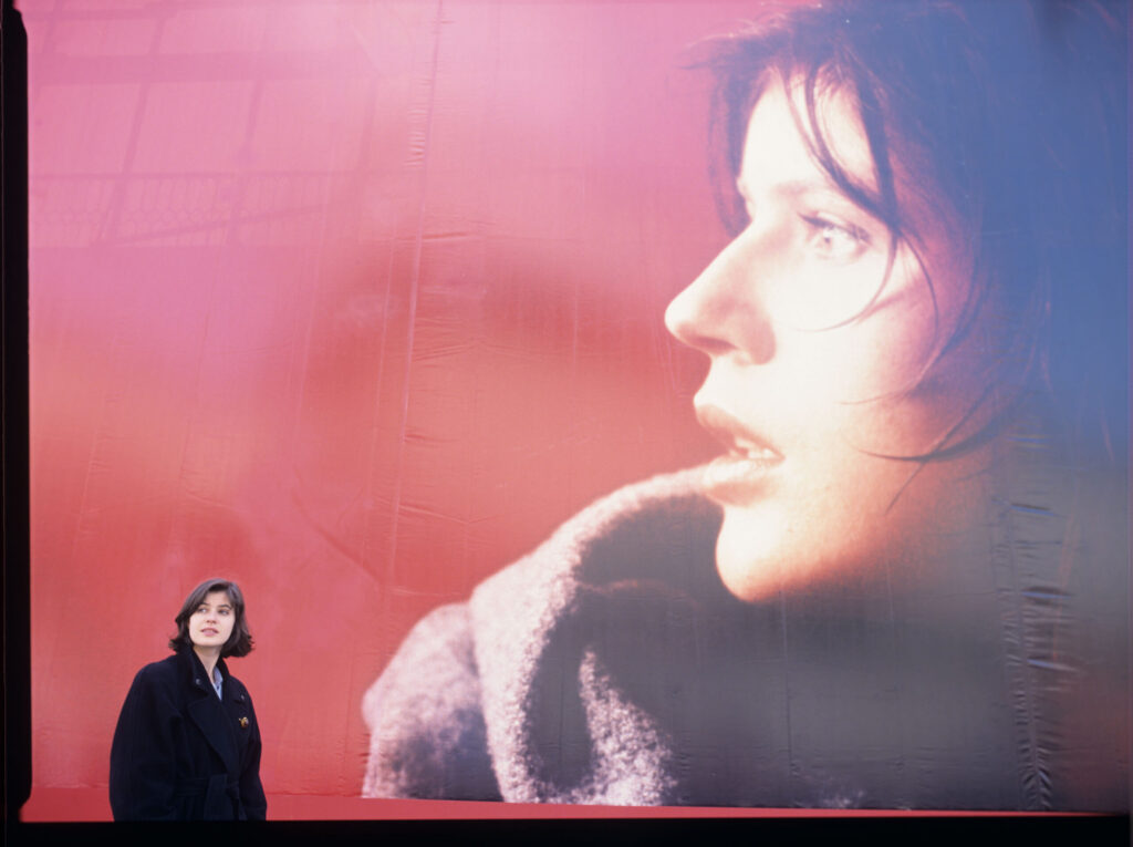 Irène Jacob in front of an advertising billboard with the likeness of her film heroine.