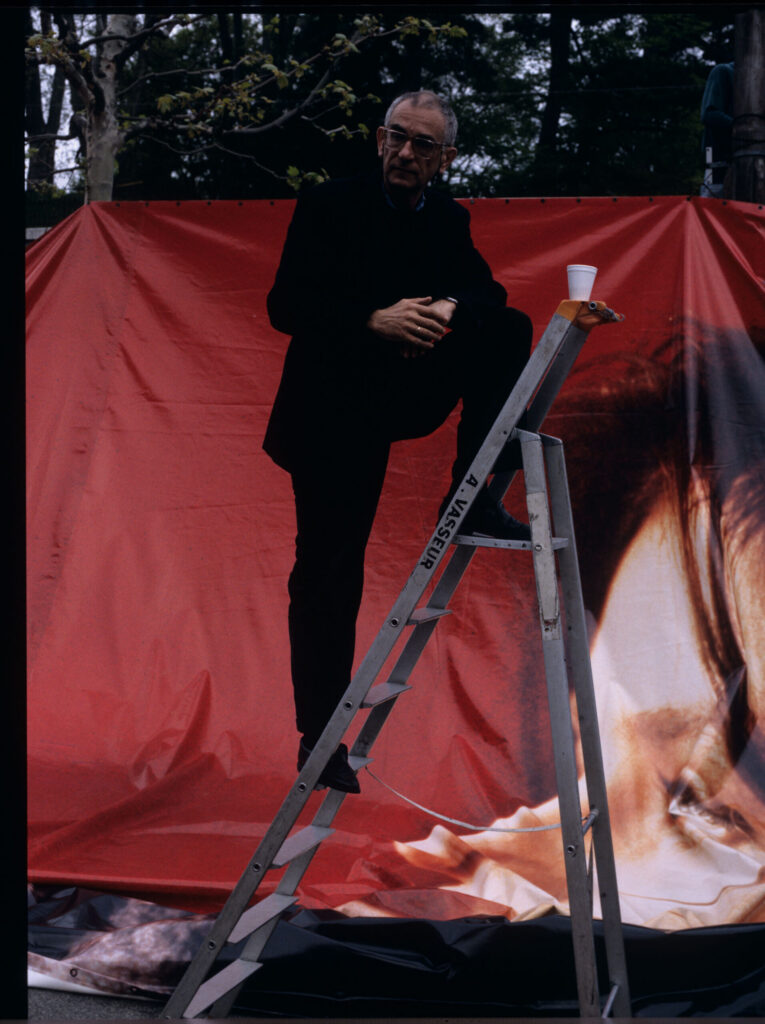 Krzysztof Kieślowski (director) dismantling an advertising billboard with the image of Valentine.